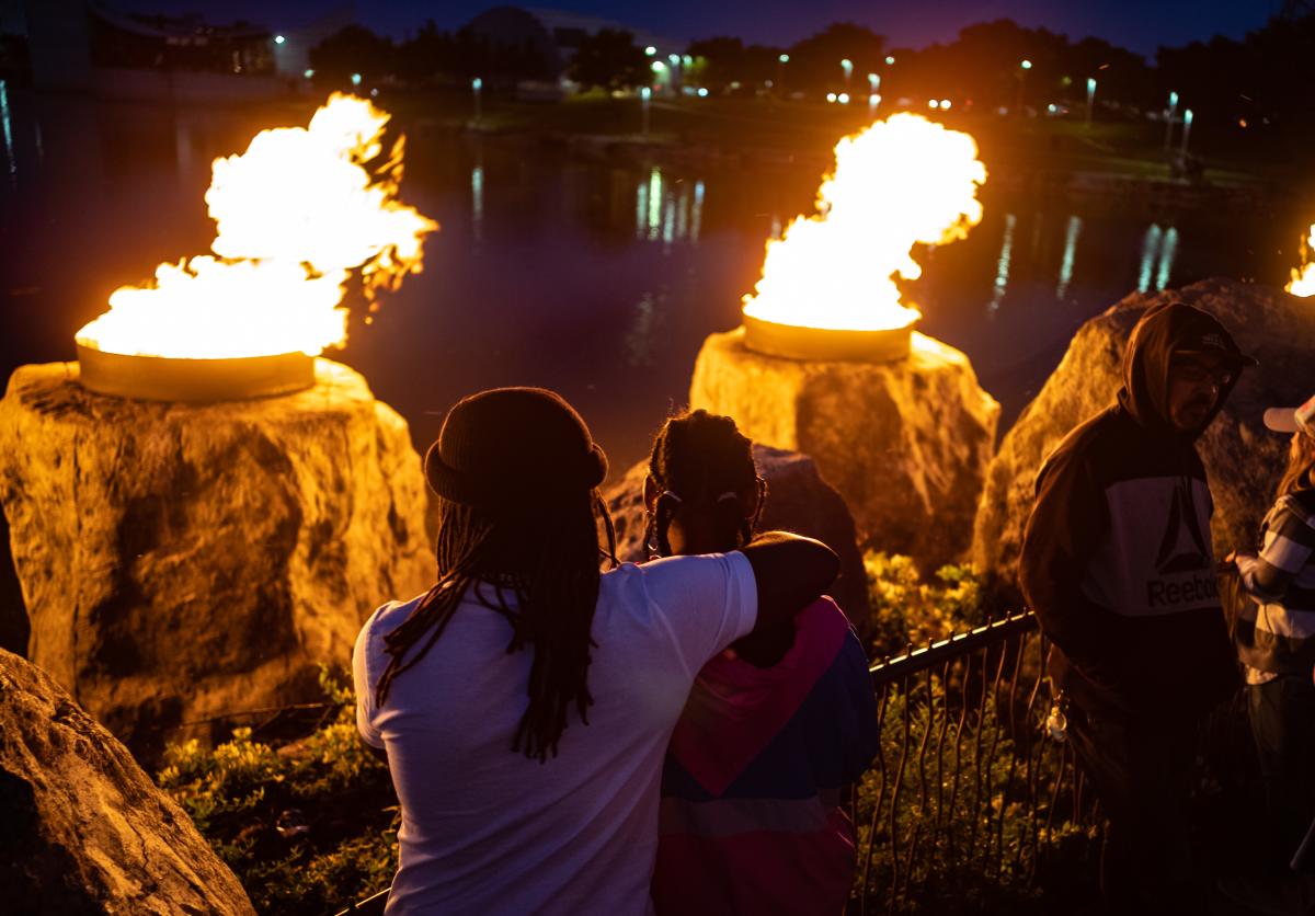 People look over the ring of fire at the Keeper of the Plains