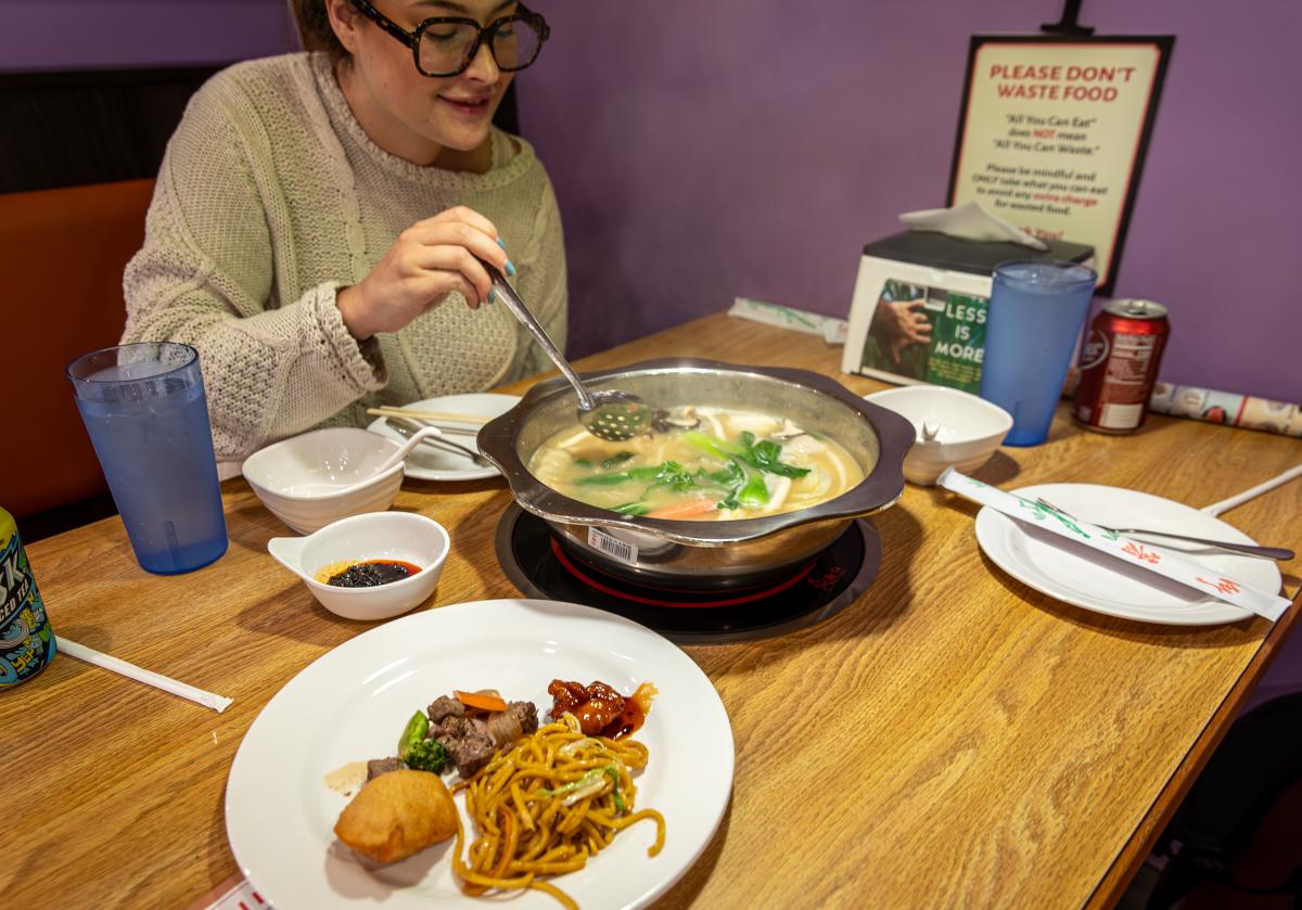 A girl mixing her ingredients into her hot pot