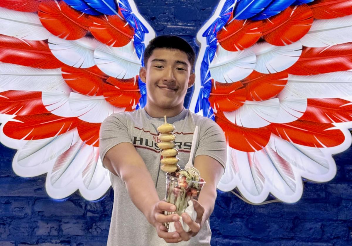 A teenager holding a treat from Tipico Helado in front of an art mural of wings.