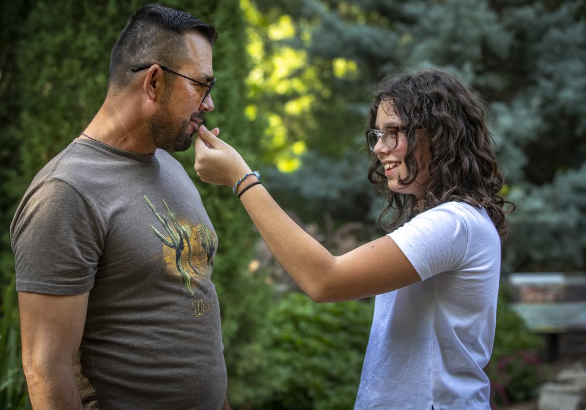 A teenage Hispanic girl hold a flower up to her father's nose at Botanica Wichita