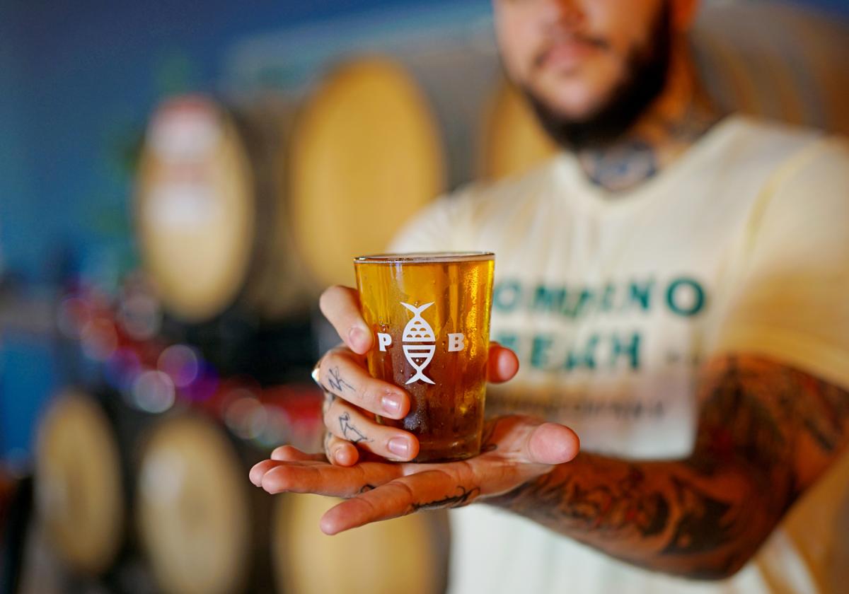 A person showcasing a beer from Pompano Beach Brewing