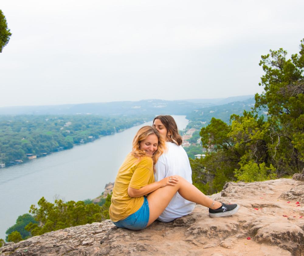 Two woman sitting close atop Mount Bonnell.