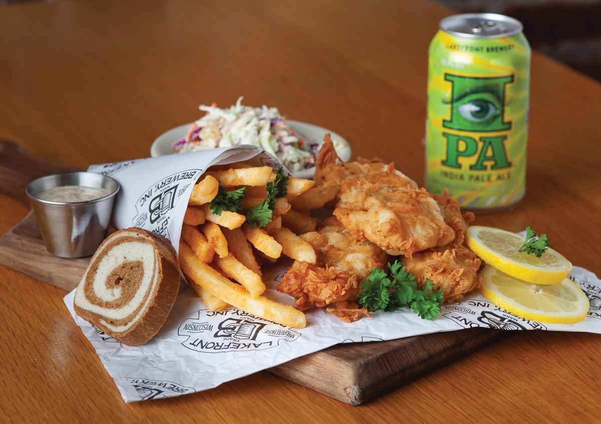 A painted figure sitting on a crescent moon hangs from the arched brick ceiling inside the Miller Caves.A fish fry with fried cod, fries, coleslaw, rye bread, lemon slices and a can of IPA served on a wooden board.