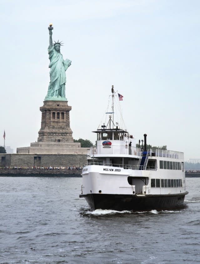 daytime view of the statue of liberty with a tour boat
