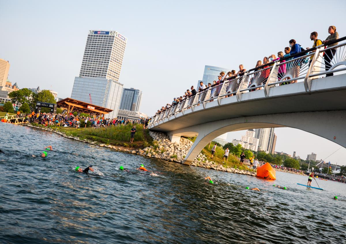 wide shot of USA Triathlon atheletes jumping into the lagoon next to Discovery World