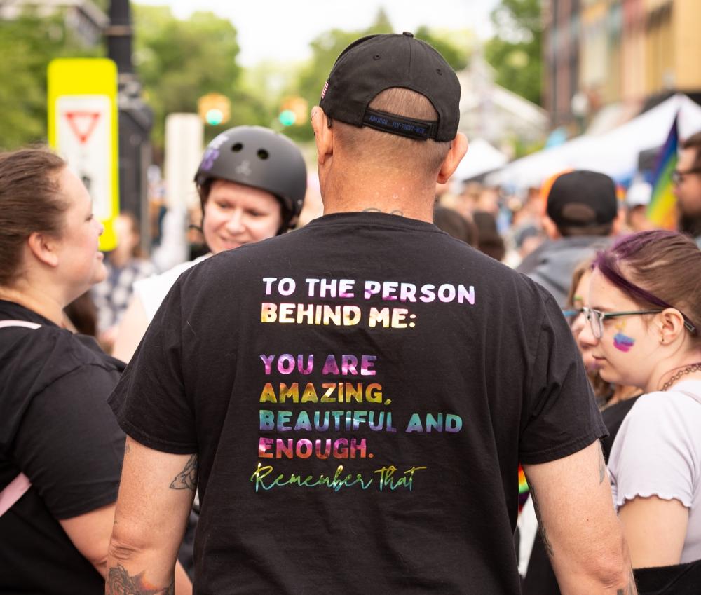 Person at Ypsi Pride with kind message on back of shirt that reads "To the person behind me: You are amazing, beautiful, and enough. remember that"
