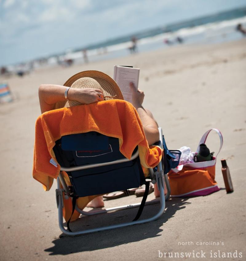 A person sitting on a chair, at the beach, reading a book in the brunswick islands