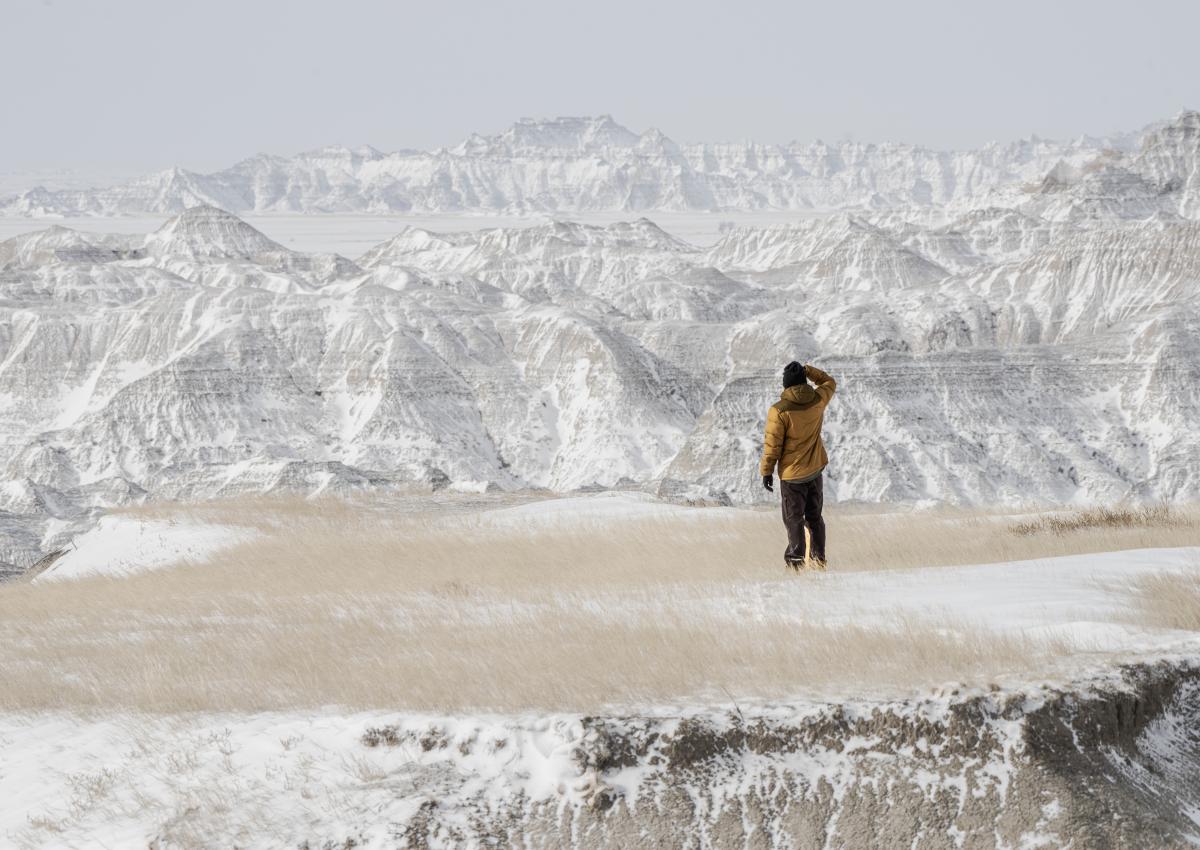 person exploring the beauty of badlands national park dusted in snow in the winter