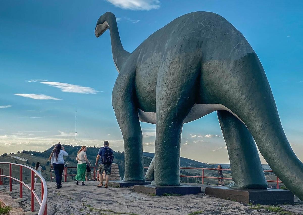 visitors standing below the brontosaurus at dinosaur park in rapid city south dakota