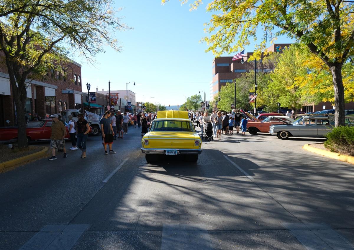 classis cars lining the streets of downtown rapid city, sd with people walking around looking at them