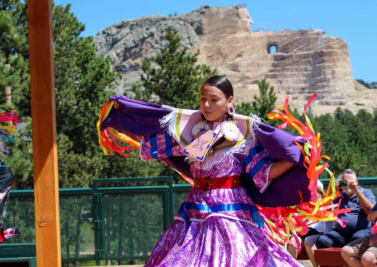 Native American dancer with colorful regalia in front of Crazy Horse Memorial®