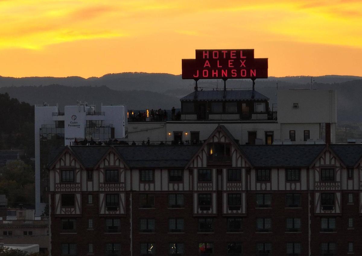 Hotel Alex Johnson sign in front of the sunsetting over the black hills in rapid city south dakota