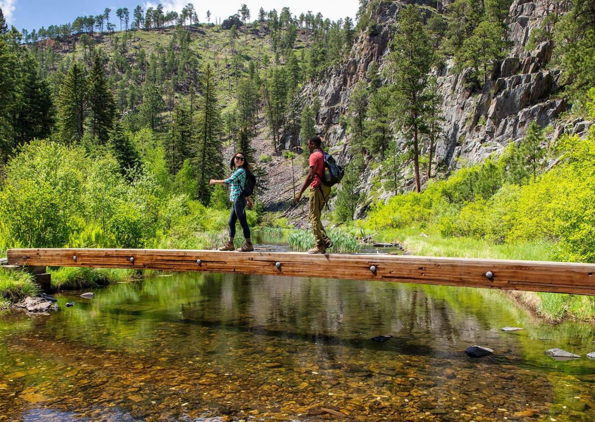 Two hikers cross a bridge on the spring creek portion of the centennial trail in south dakota