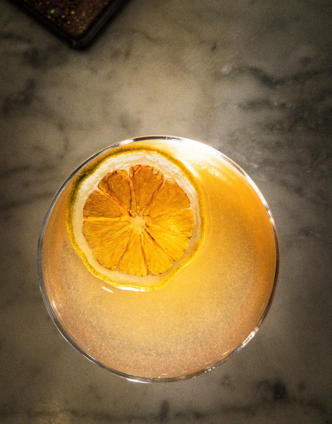 Orange garnish floats in ice of a craft cocktail