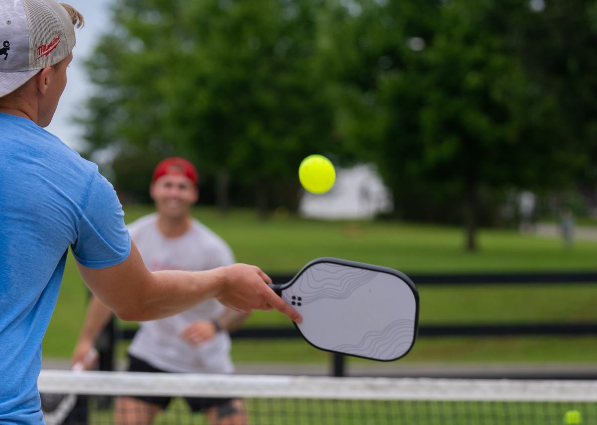 a man hitting a pickleball in a game at freeman lake