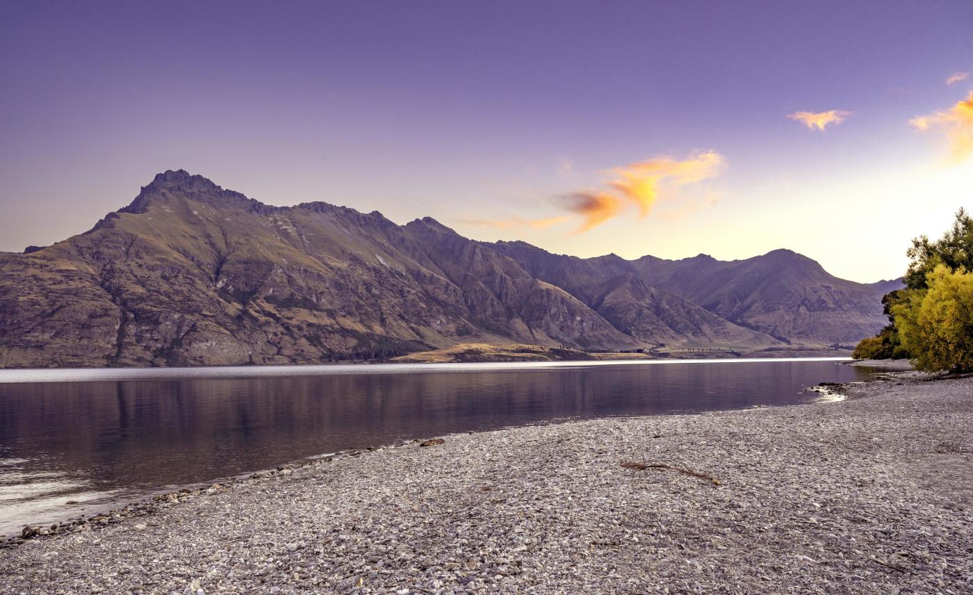 Scenic photo of lake and mountains taken at sunset.