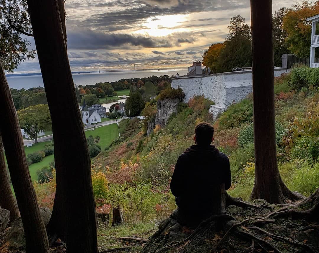 Silhouette of man sitting in the woods overlooking Mackinac Island and the Mackinac Bridge