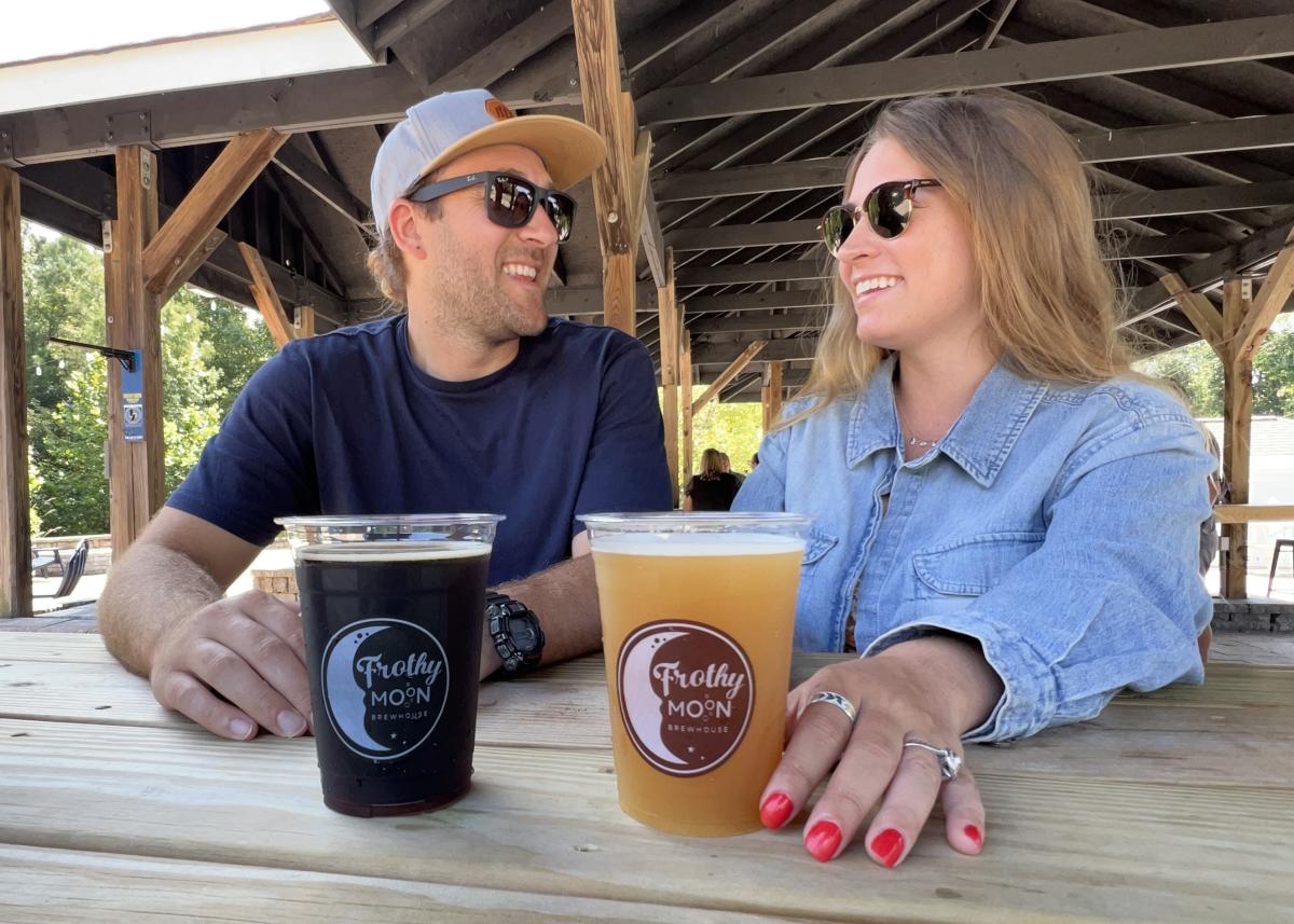 Couple drinking beers on a patio at Frothy Moon Brewhouse