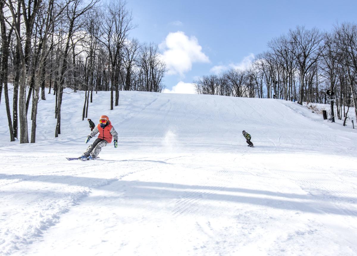 Three snowboarders on a wide open downhill run