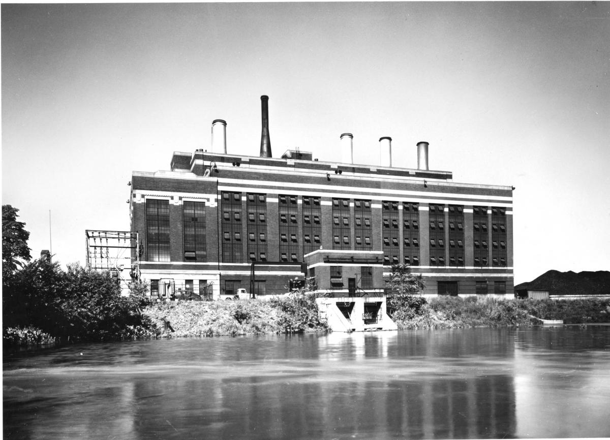 Historic exterior shot of the City Light and Power Company. A brick building with five smoke stocks prominently on the roof.