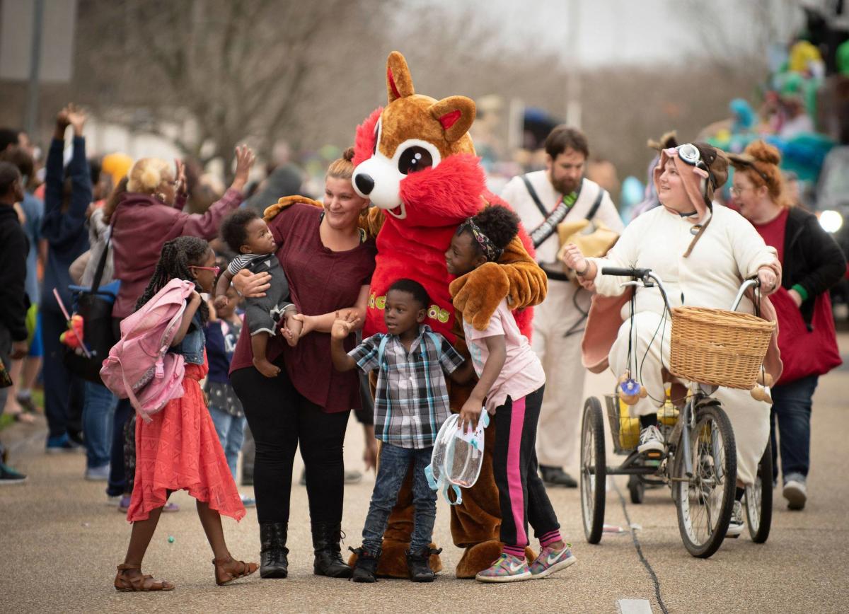 Family taking photo with Mid City Gras squirrel mascot