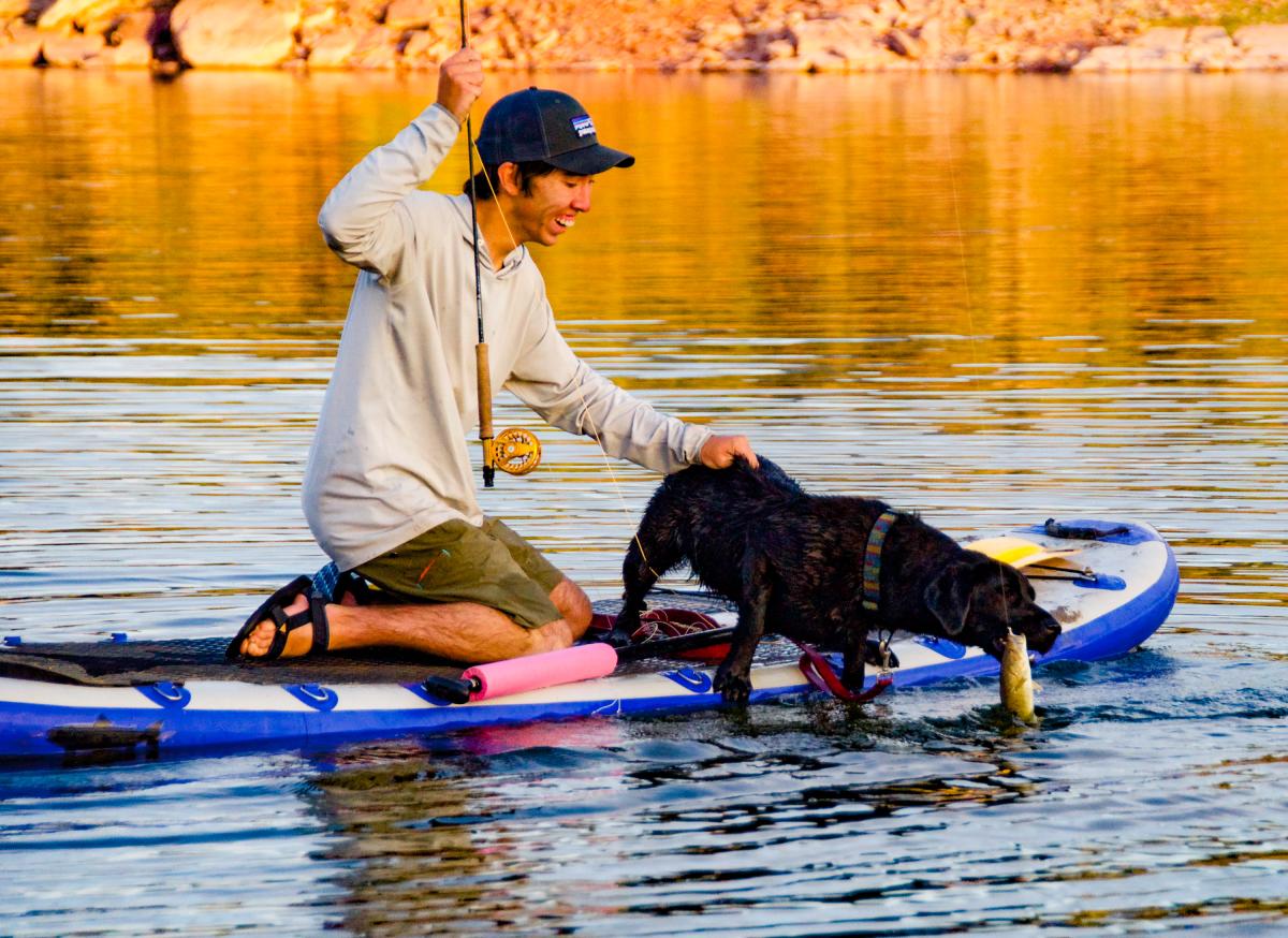 Man and dog on SUP or Standup Paddle board while fishing on Flaming Gorge