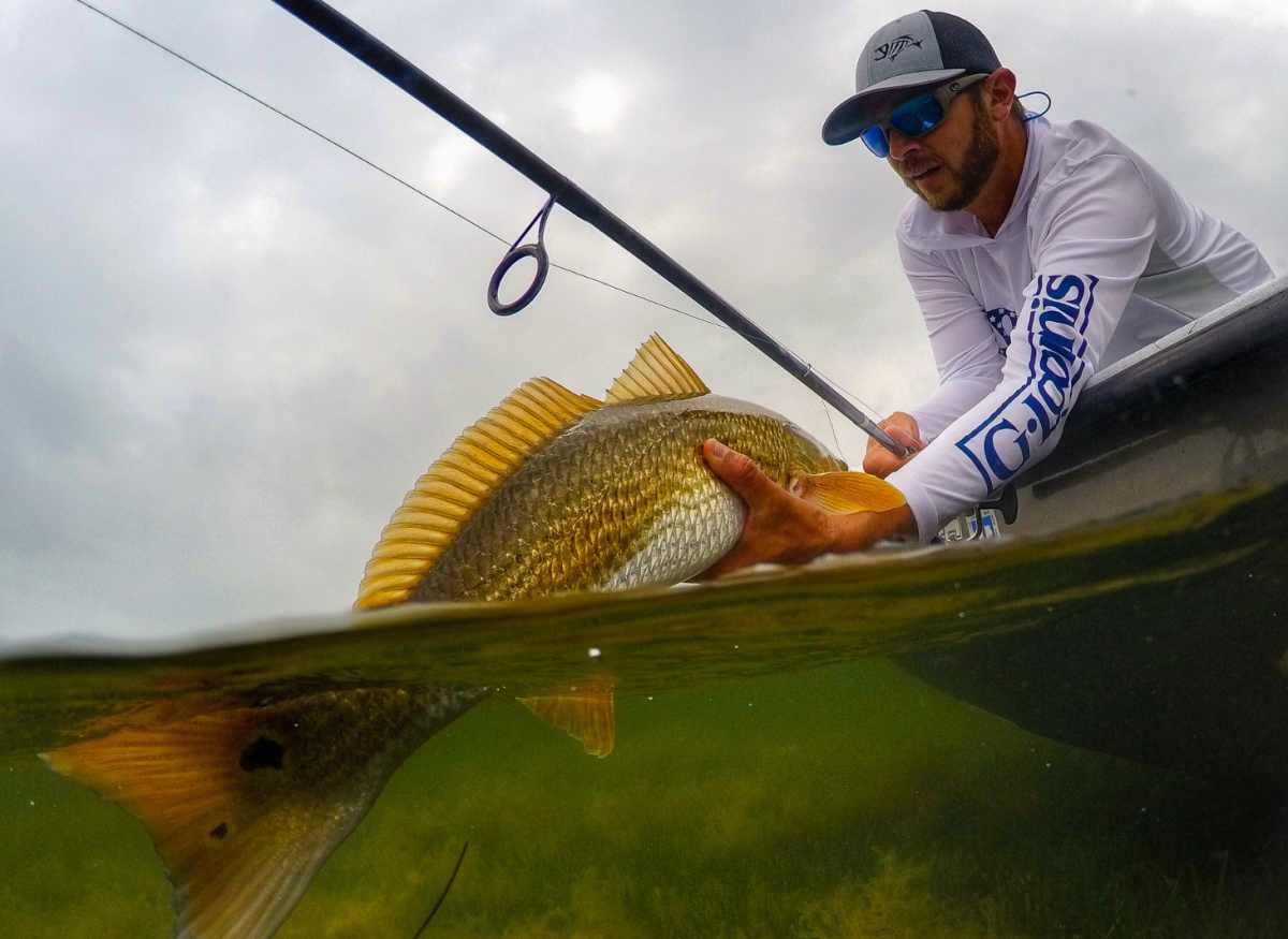 A man on a boat pulls a large fish out of the water in Port Aransas, Texas