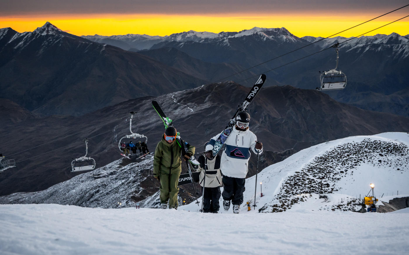Skiers walking up mountain at Coronet Peak Night Ski during sunset