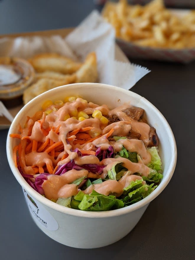 A paper cup of bulgogi with yum yum sauce with fries in the background at Covington Yard