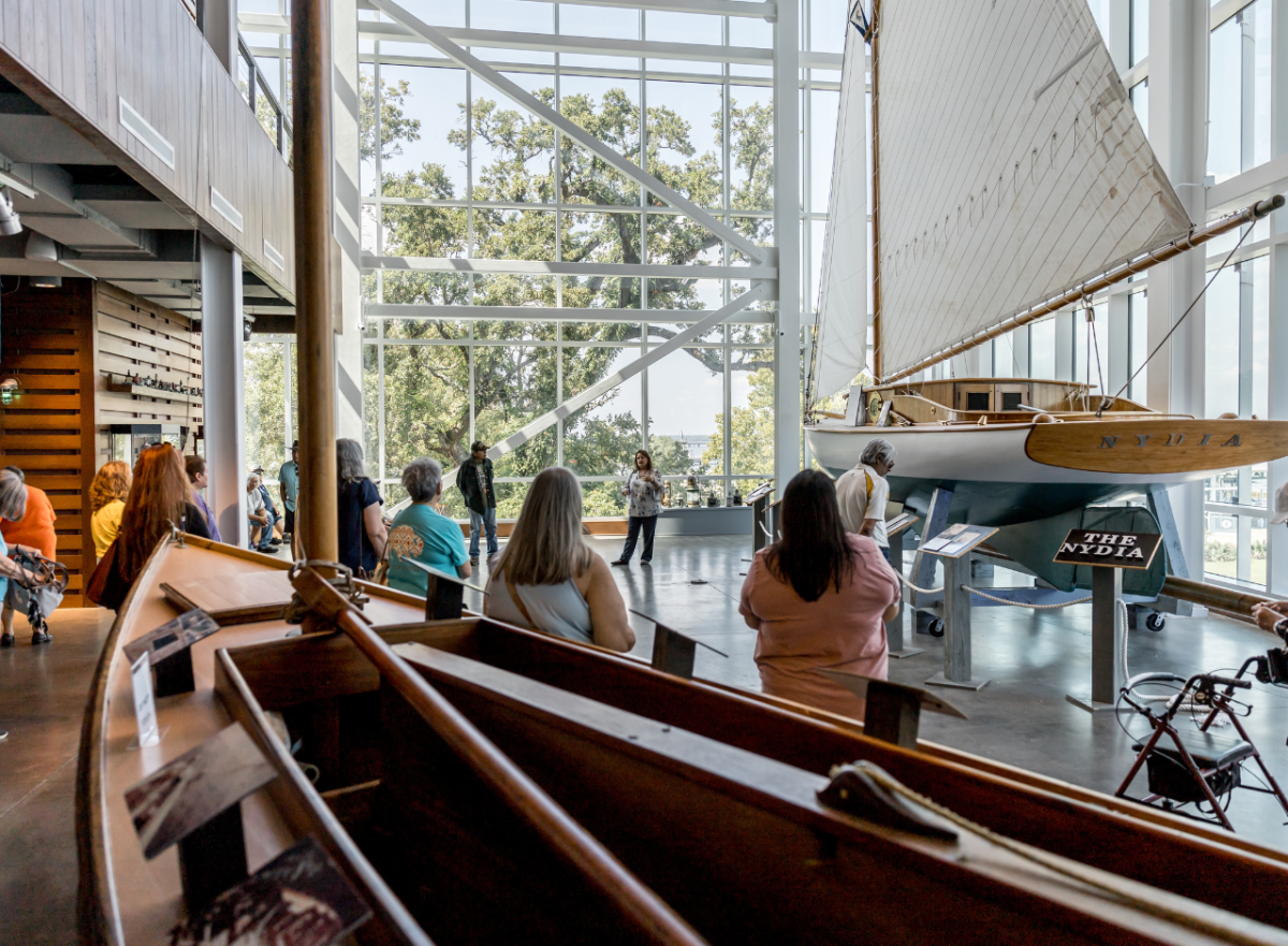 Interior of Maritime & Seafood Industry Museum with sailboats on display and tourists viewing exhibit