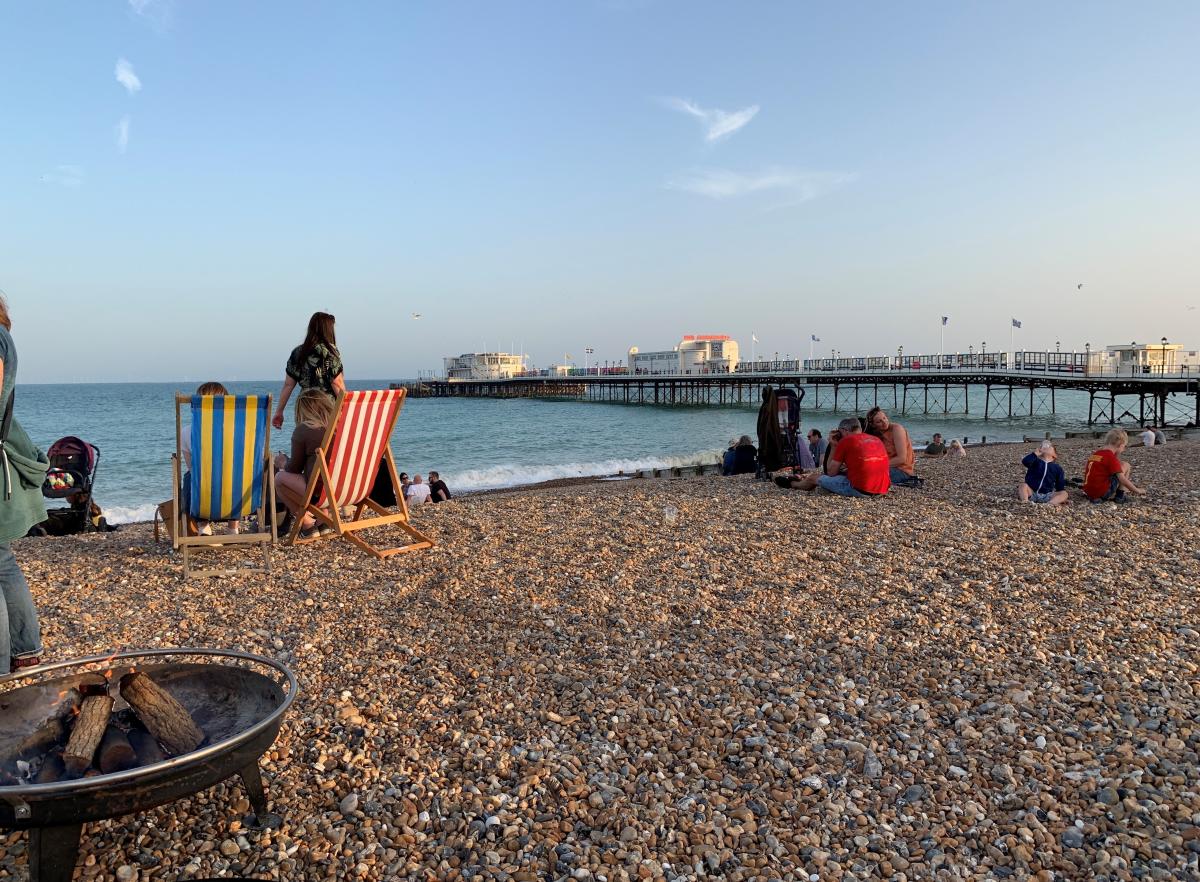 Group of people enjoying a BBQ on the beach at Worthing, with a view of Worthing Pier