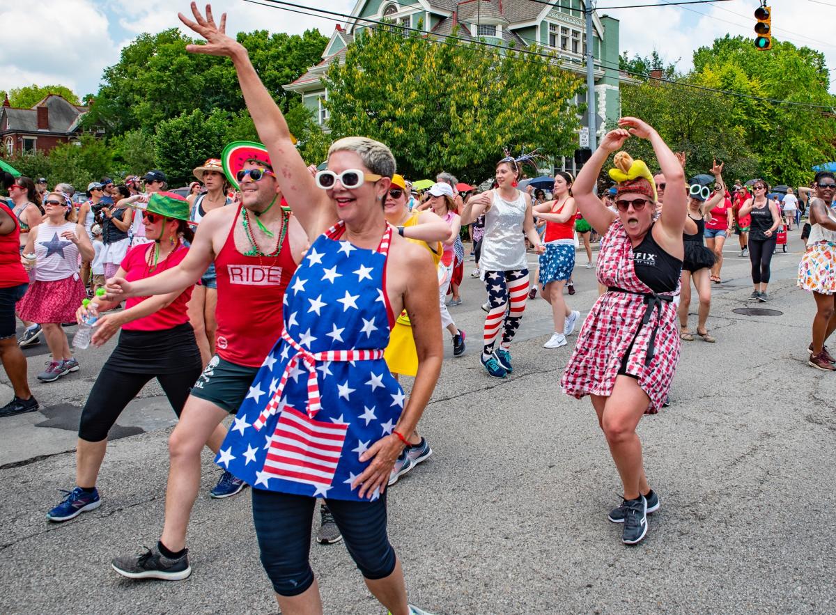 Image is of people walking down the street who are in the parade dressed in USA garb.
