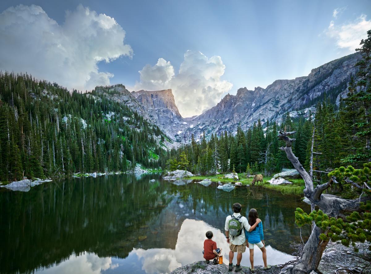 A family at a tranquil mountain lake nestled among vibrant trees and rocky formations, reflecting the surrounding nature.