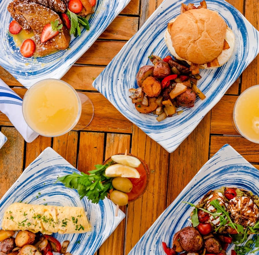 an overhead photo of four brunch dishes including an omelette, french toast