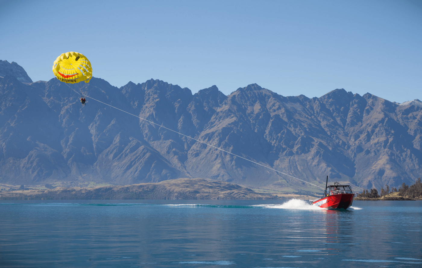 Boat towing a parasail in front of the remarkables