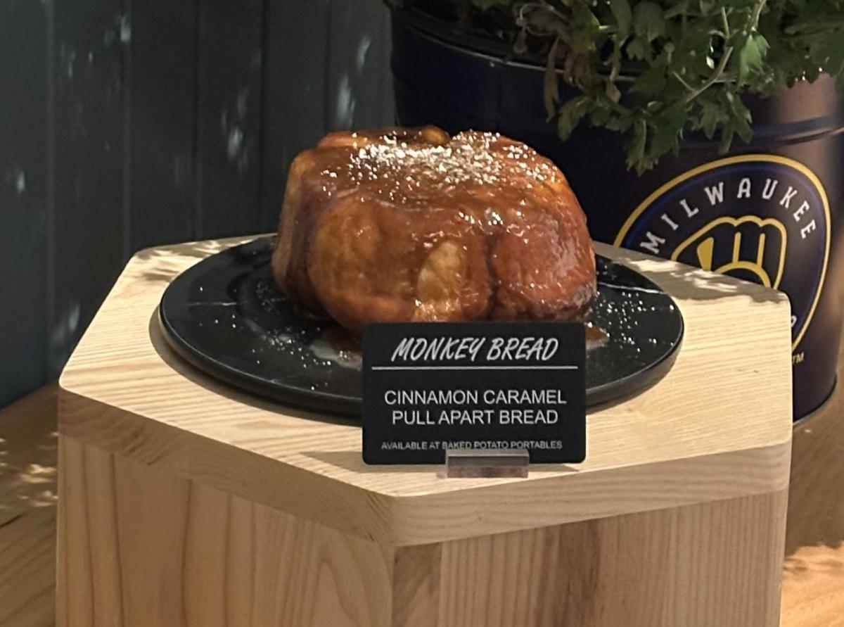 Cinnamon caramel monkey bread displayed beside Milwaukee Brewers-themed flowers, with a specialty hot dog in the foreground.