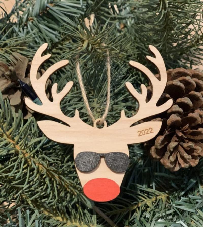 Christmas tree ornament made out of wood and shaped like a reindeer wearing sunglasses