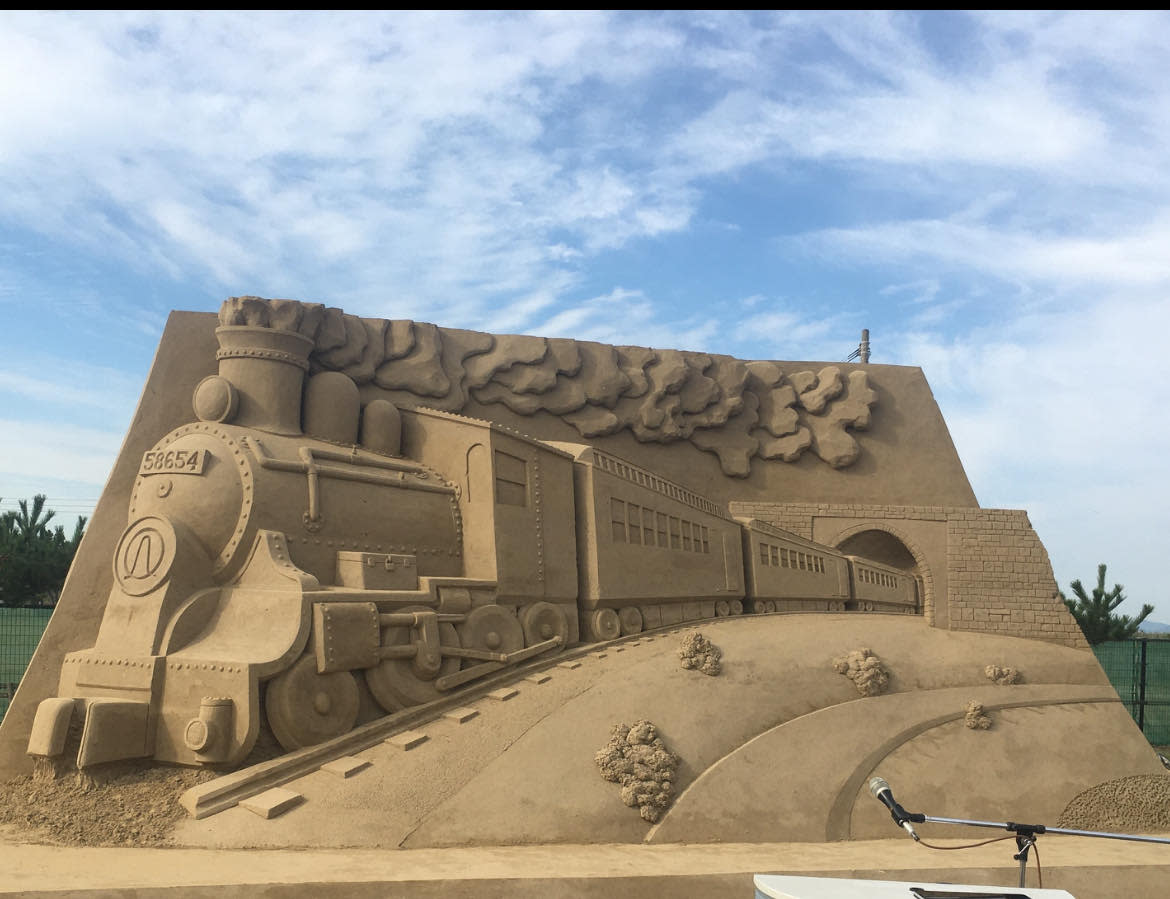 Sand sculpture showing a train coming out of a tunnel