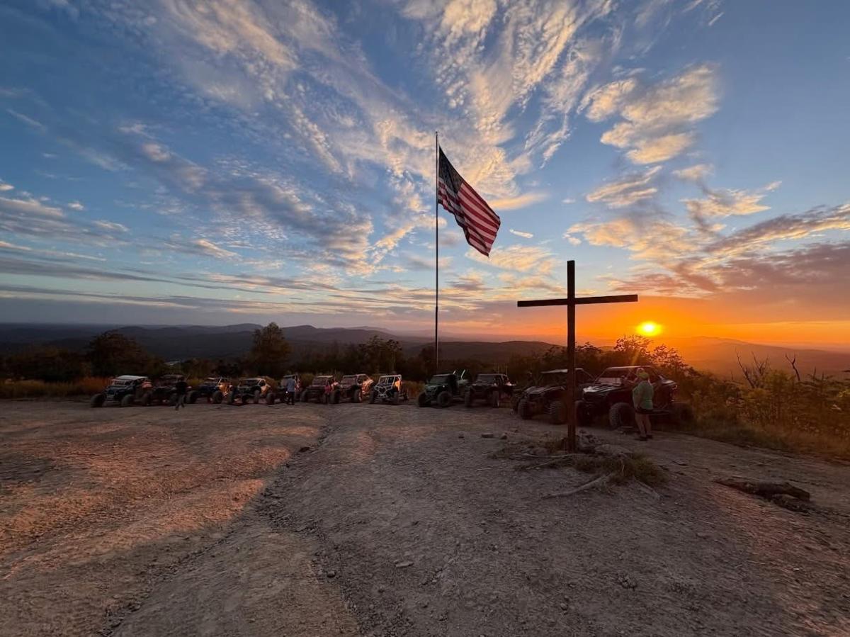 atvs lined up at the overlook with a beautiful sunset, cross, and flag at indian mountain atv park