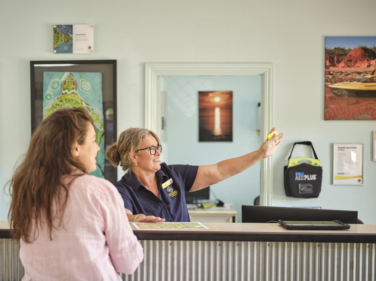A friendly staff member helping a guest at the RAC Cable Beach Holiday Park