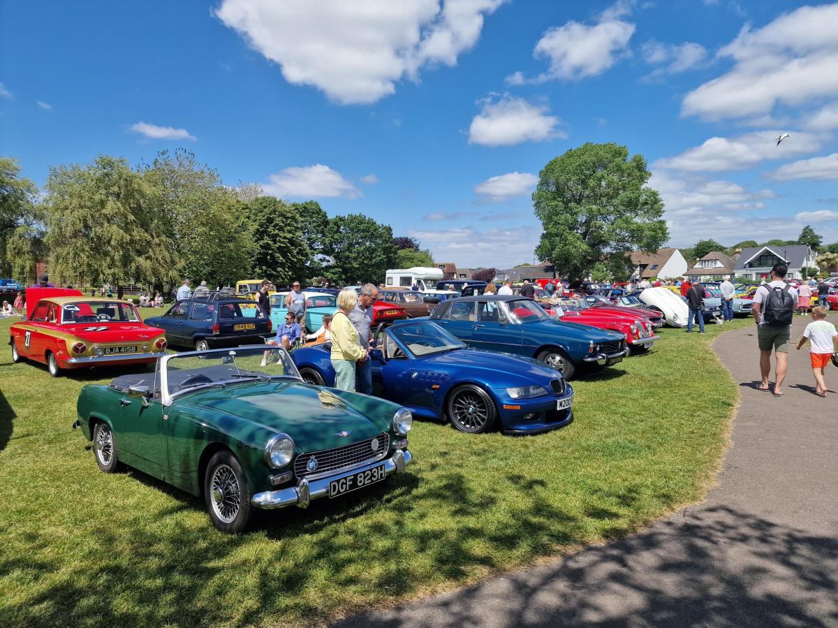 Classic Cars on the grass with people stopping to look