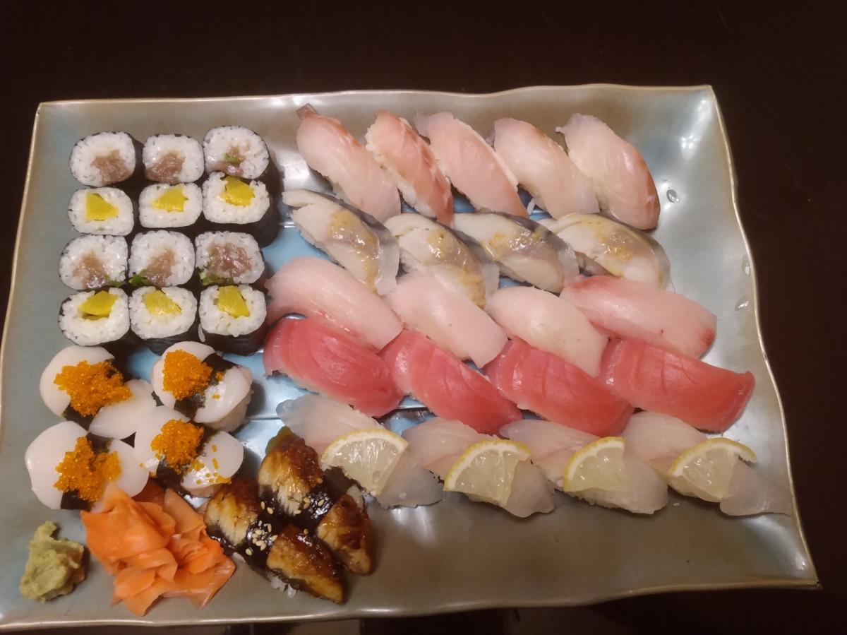 Image is of a variety of sushi on a silver, square plate.