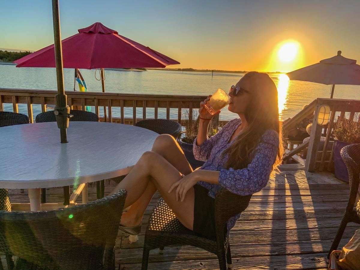 A woman enjoys waterfront views with a drink from Front Street Grill at Stillwater