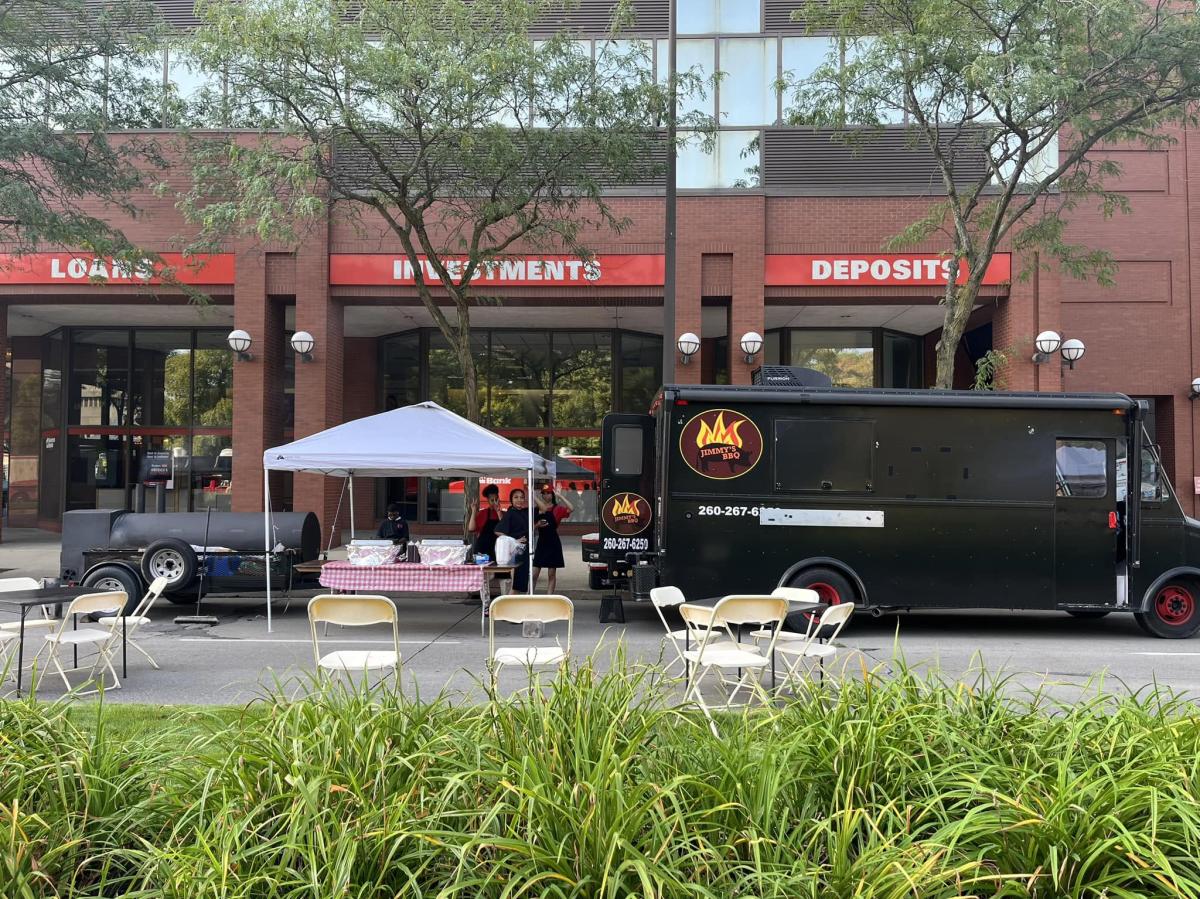 Jimmy's BBQ food truck parked on Main Street in Fort Wayne, Indiana. Three workers stand outside waving at the camera.