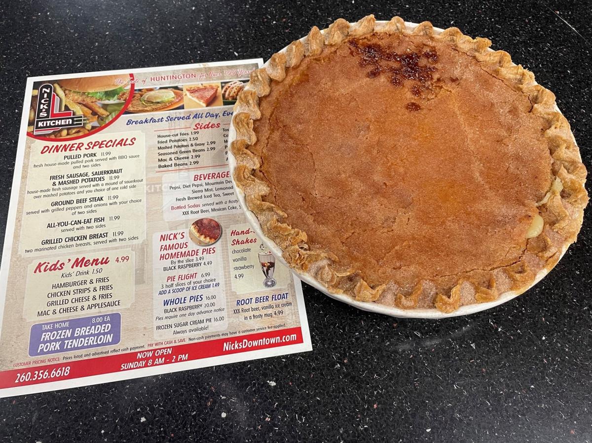 A pie from Nick's Kitchen next to a menu