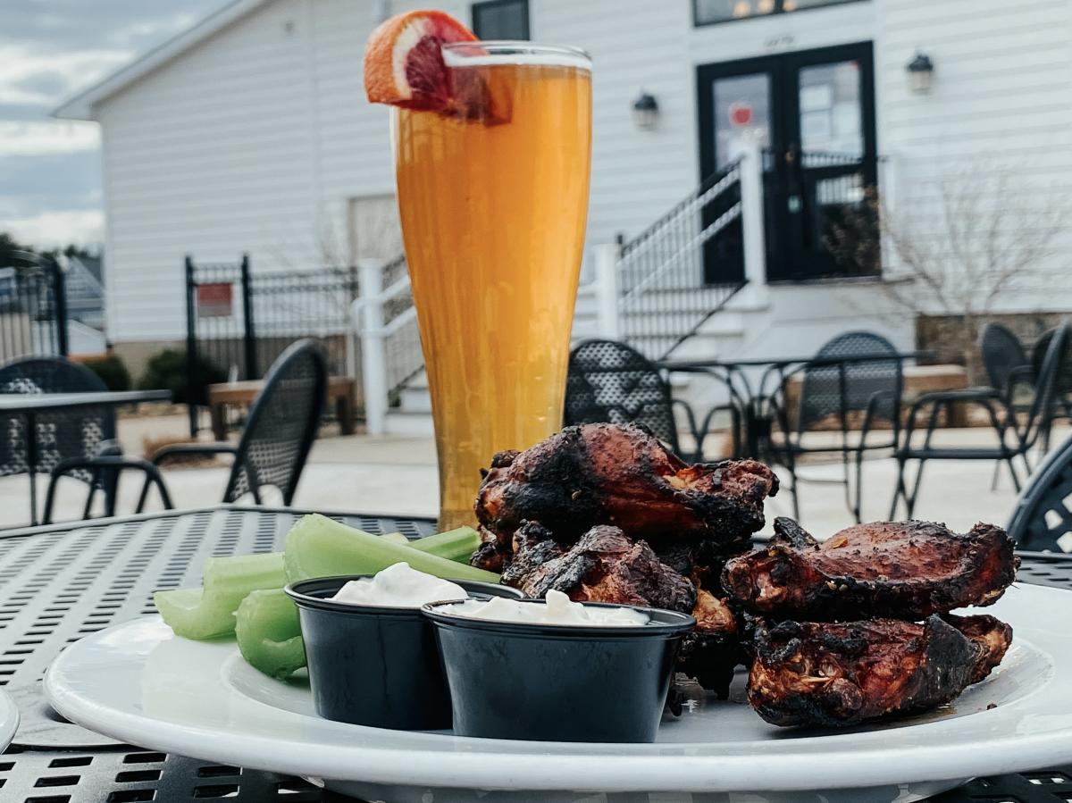 A plate of BBQ and a beer on a table outdoors