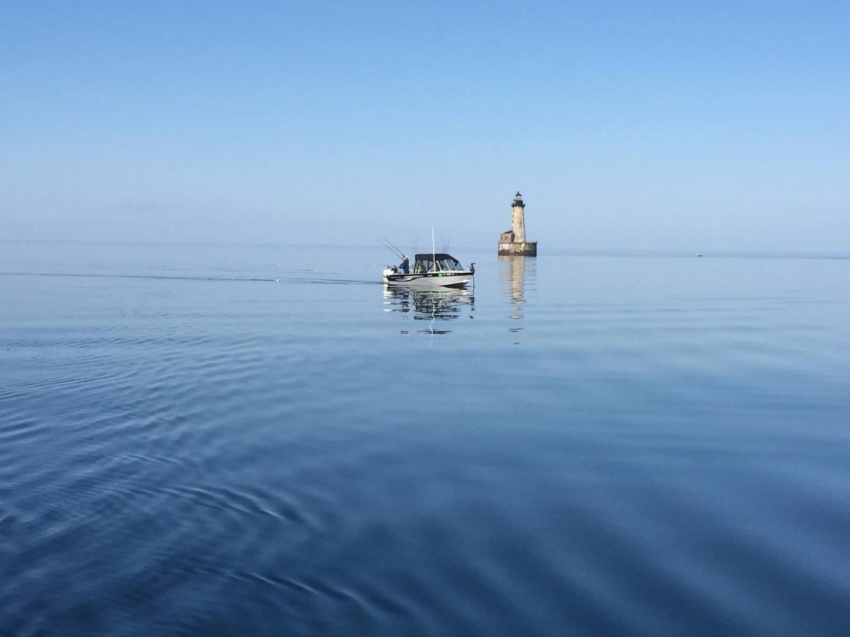 Fishing boat on open water in front of Stannard Rock Lighthouse.