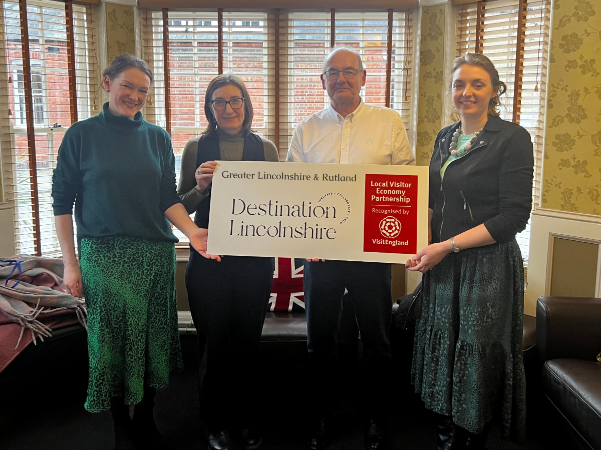 Four business people hold an enlarged poster promoting the Destination Lincolnshire brand
