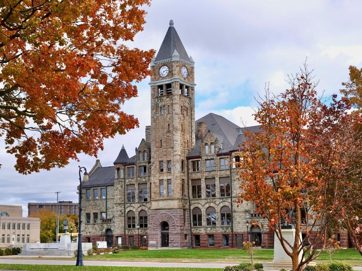 View of the historic Hackley Administration Building in Muskegon, Michigan - with its prominent clock tower, surrounded by vibrant autumn foliage.
