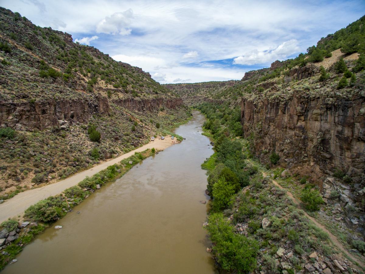 Aerial view of the Rio Grande flowing through a rugged canyon with lush green vegetation along its banks.